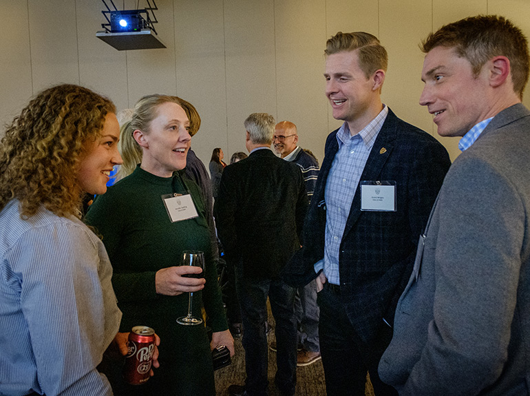 A group of Econ students and alumni mingle at an event